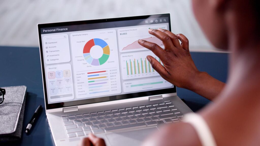 Person tracking debt payoff progress and budgeting on a laptop in a minimal home workspace